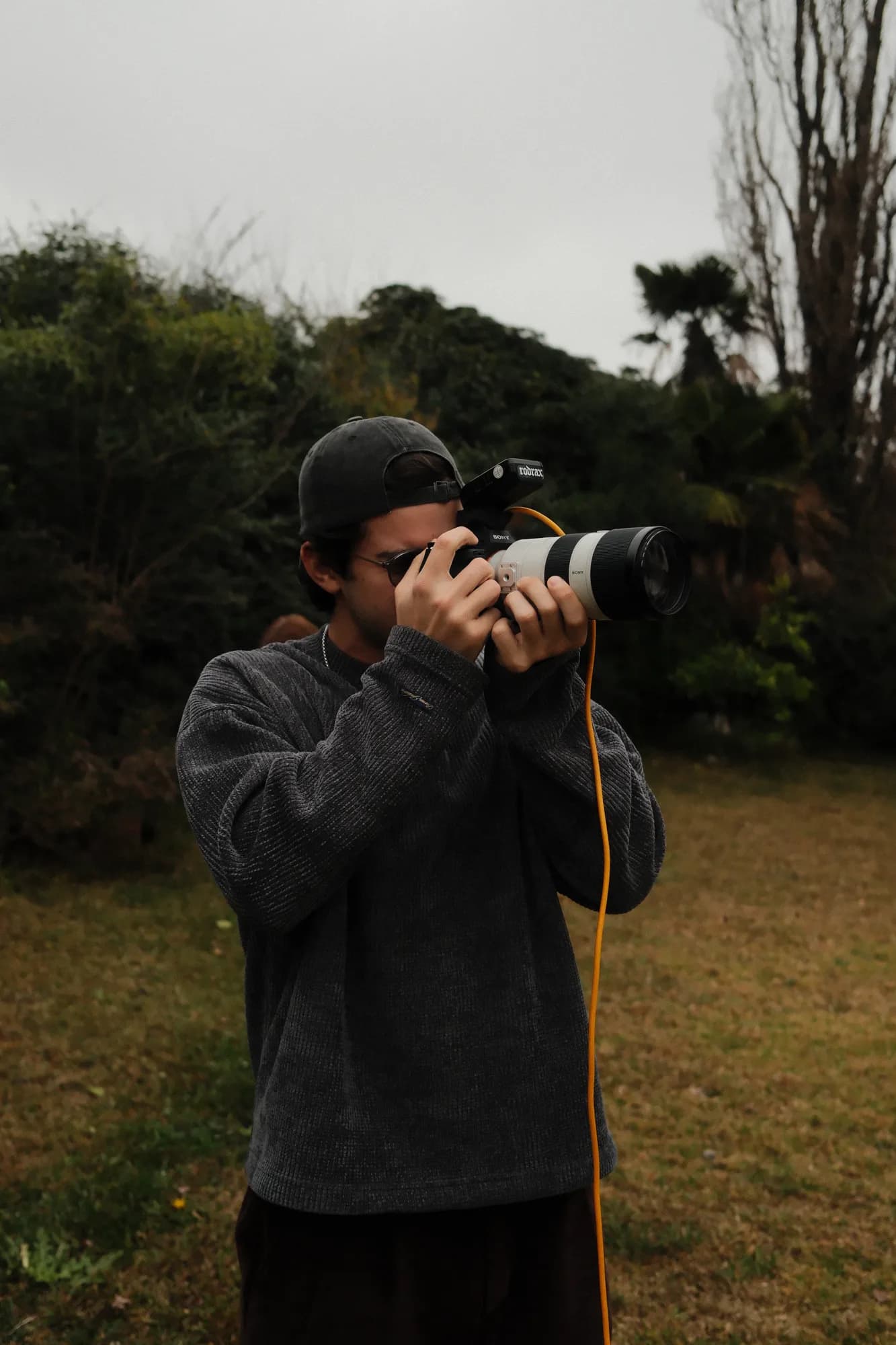 Rodrigo fotografiando con un teleobjetivo al aire libre, en un exterior nublado