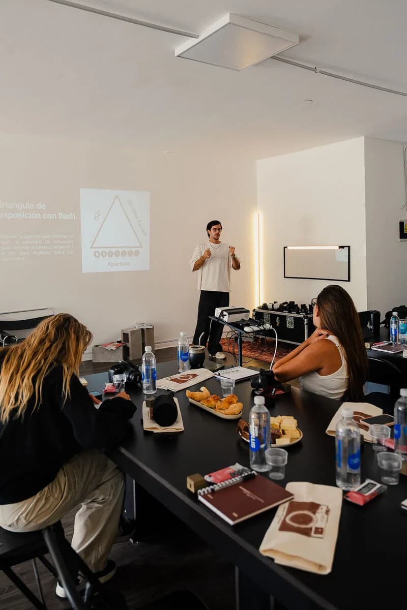 Alumnos alrededor de la mesa durante la charla, con el proyector de fondo